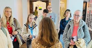 A group of people listen to a talk in a gallery