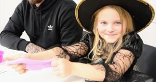 A girl in a witch's hat and Halloween costume
