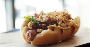Hot dog with fried onions and a herbal garnish.