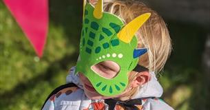 A child wearing a green dragon mask
