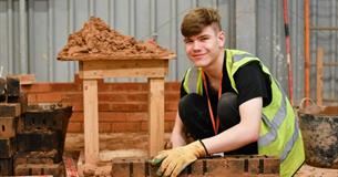 3. A young man works on a brick wall, arranging bricks skillfully to form a solid and even surface.