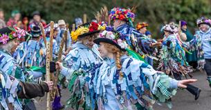 Members of the Dartmoor Border Morris dancing together in their ribbon-covered outfits