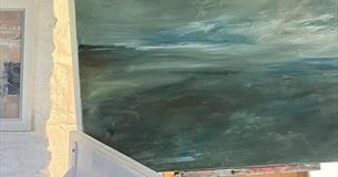 A landscape painting on an easel in an artist's studio