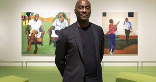 A photograph of a man standing in a gallery
