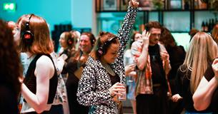 A girl dressed in black and white and holding a drink dances at a silent disco