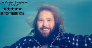A man in a plaid shirt is shown underwater. He is smiling.