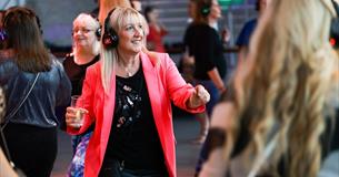 Photograph showing a woman dancing whilst wearing headphones