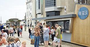 Customer queuing outside The Greek also customers sat at outdoor seating area.