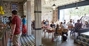 The inside of Boston Tea Party showing customers  at the counter ordering food and drinks and other customers seated at tables.