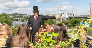 A man dressed as IK Brunel showing a group the Royal Albert Bridge
