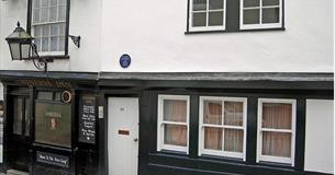 The black and white painted exterior of the Minerva Inn with large lantern hanging outside above the pavement.