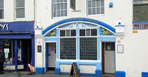Exterior of The Dolphin with blue painted exterior, stain glass windows and painted dolphins.