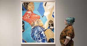 Photograph showing a woman looking at a painting of a woman