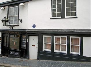 The black and white painted exterior of the Minerva Inn with large lantern hanging outside above the pavement.