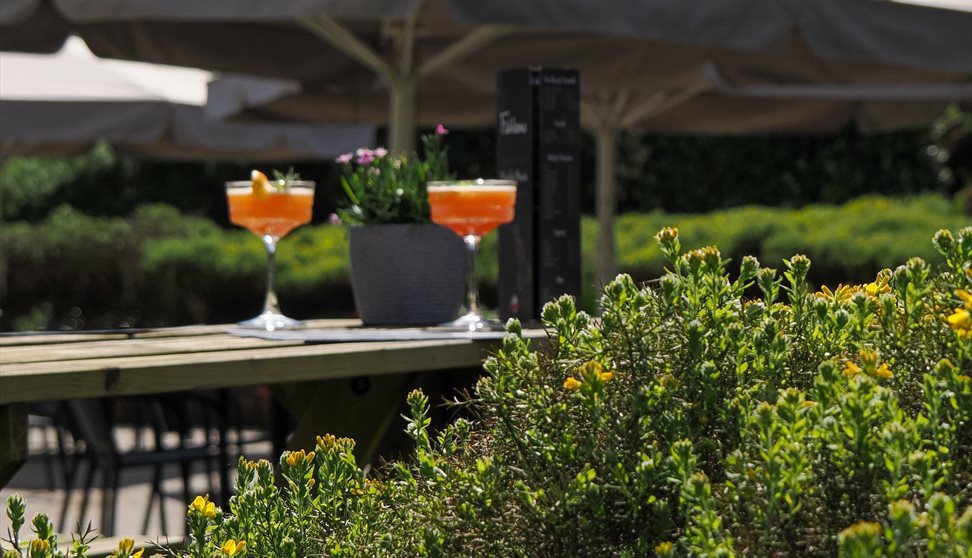 The outdoor terrace at Fishbone Restaurant, with benches, tables and chairs and giant umbrellas
