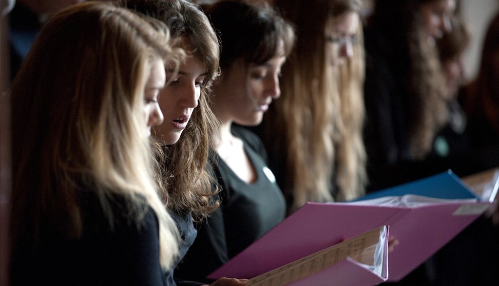 Choir members singing from sheet music