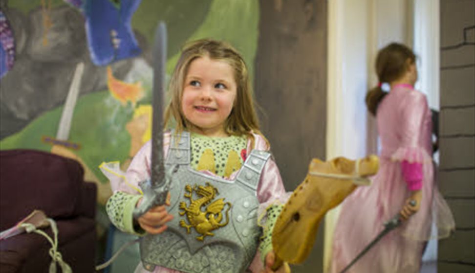 Young child dressed up as a medieval knight holding a toy sword.