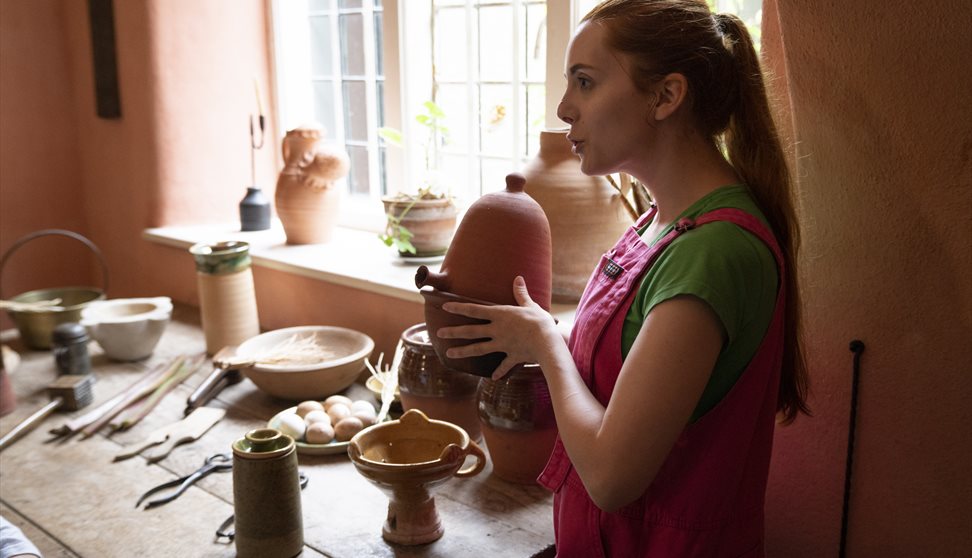 A volunteer explaining an artefact in Buckland Abbey's historic kitchen