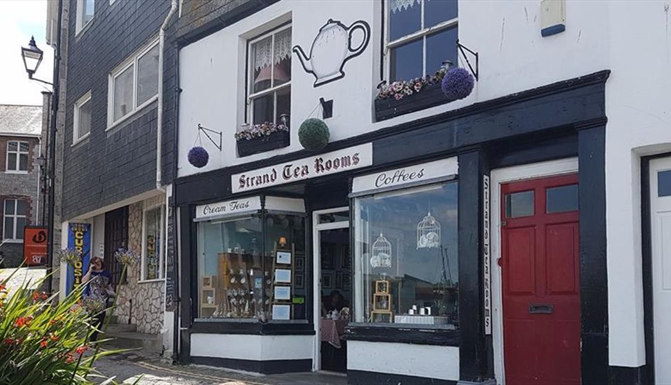 Shop front of The Strand Tea Rooms, painted black and white and with a large painted teapot above the sign.