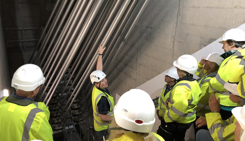 A group in high visibility jackets listen to a mad talking within the anchorage chamber