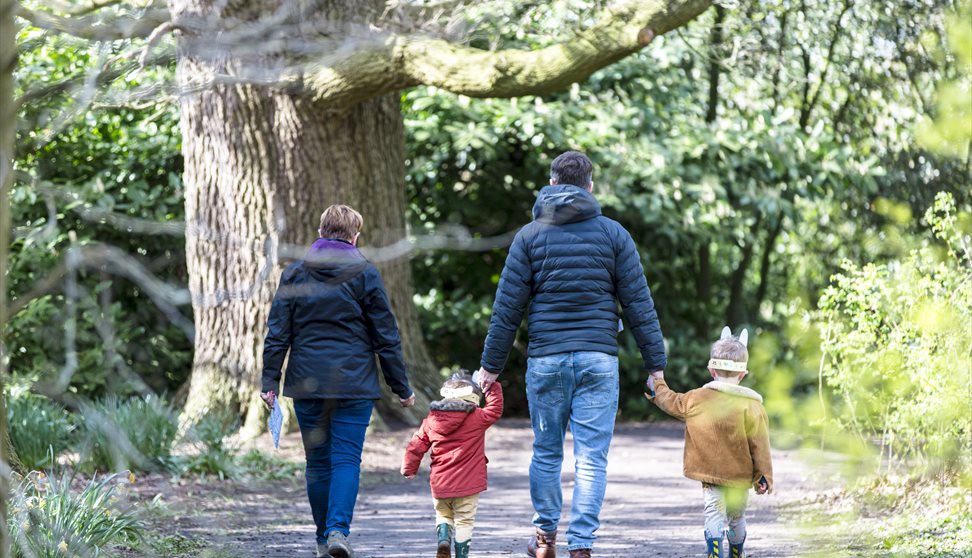 A family of four enjoy walking through Saltram garden completing their Easter trail with bunny ears on their heads.