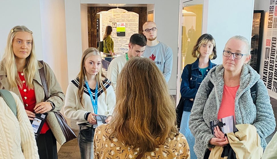A group of people listen to a talk in a gallery