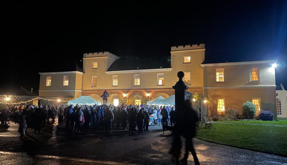 Crowd gathered in Pentillie's courtyard which is lit up ready for Christmas carols.