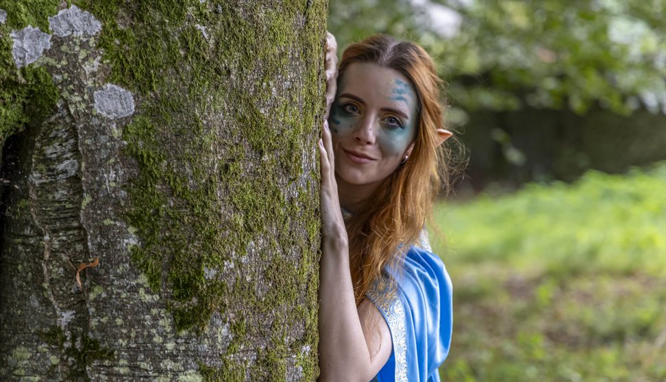 A water sprite looking out from behind a tree