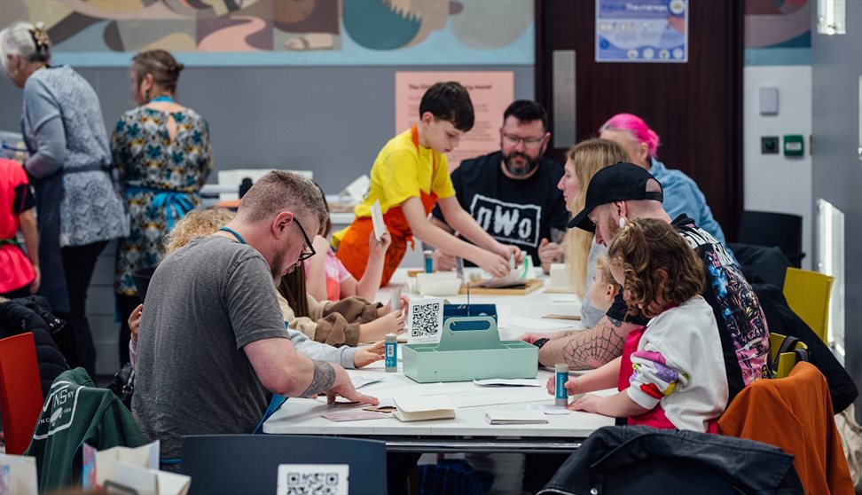 Photograph showing a busy workshop of families making craft activities
