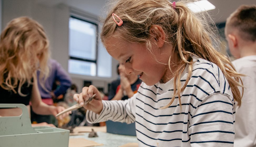 A girl in a striped top enjoys a craft activity at The Box Plymouth