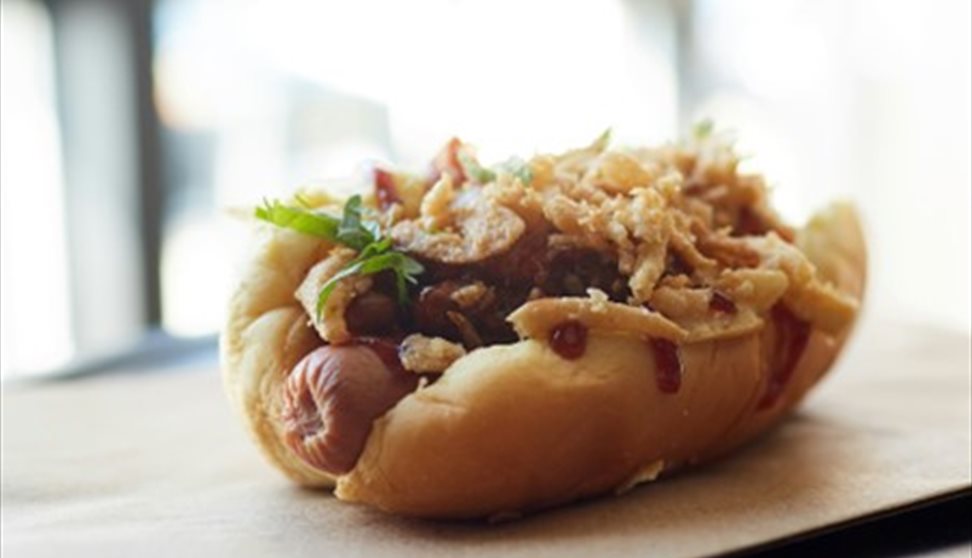 Hot dog with fried onions and a herbal garnish.