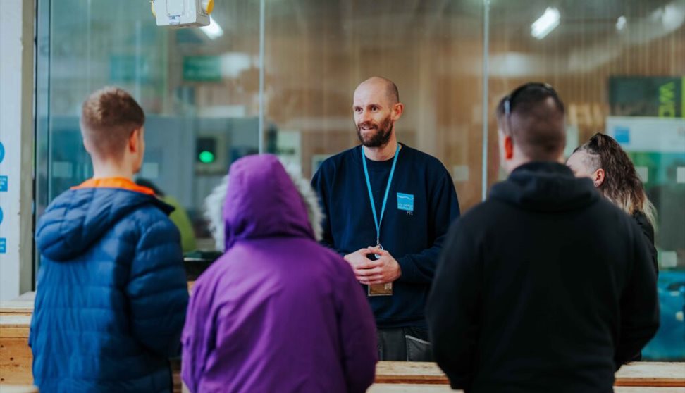 A man addresses a group of attentive individuals, standing at the forefront and sharing his insights.