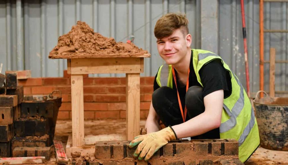 3. A young man works on a brick wall, arranging bricks skillfully to form a solid and even surface.