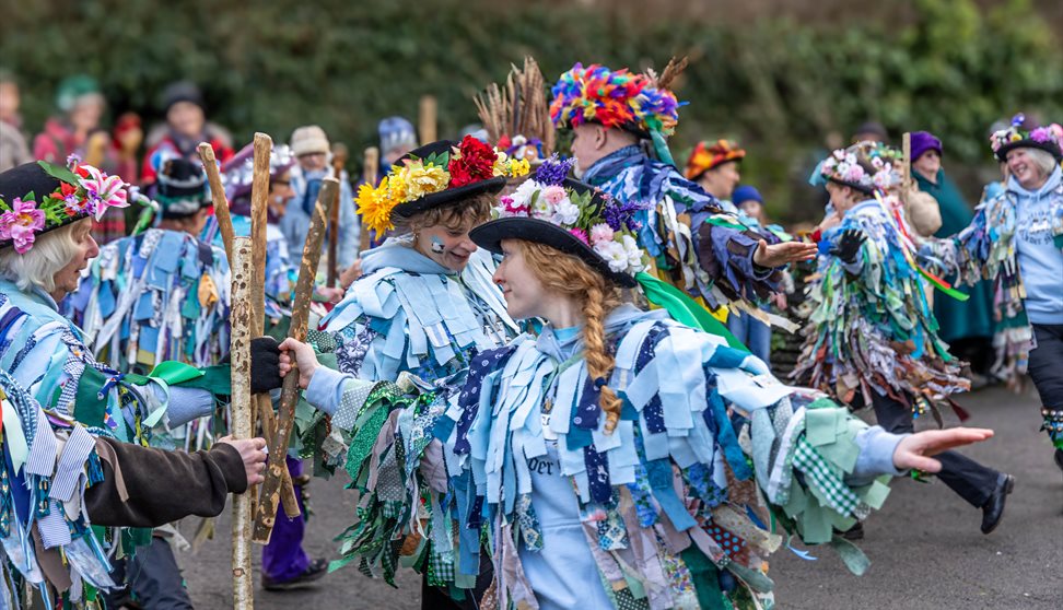 Members of the Dartmoor Border Morris dancing together in their ribbon-covered outfits