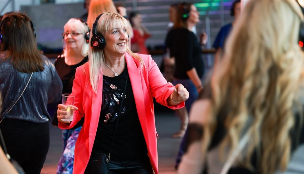 Photograph showing a woman dancing whilst wearing headphones
