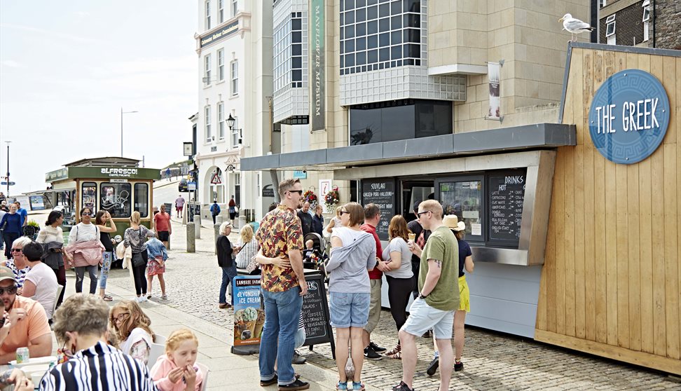 Customer queuing outside The Greek also customers sat at outdoor seating area.