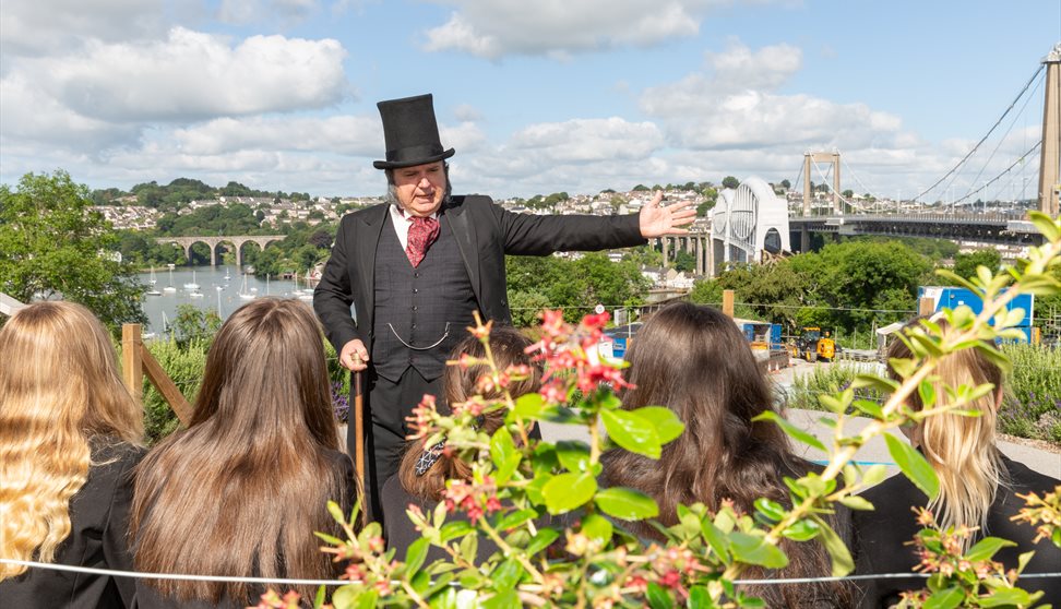 A man dressed as IK Brunel showing a group the Royal Albert Bridge