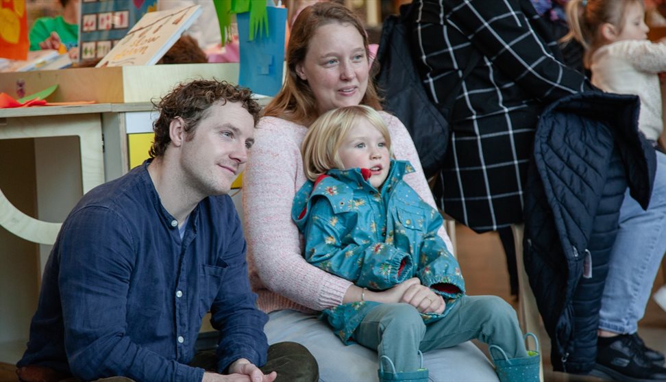 little boy sitting with his parents at the explore more area