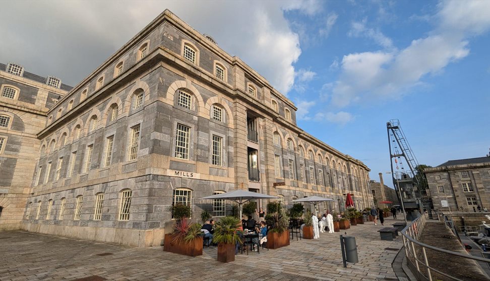 A stone brick building with umbrellas outside and people eating