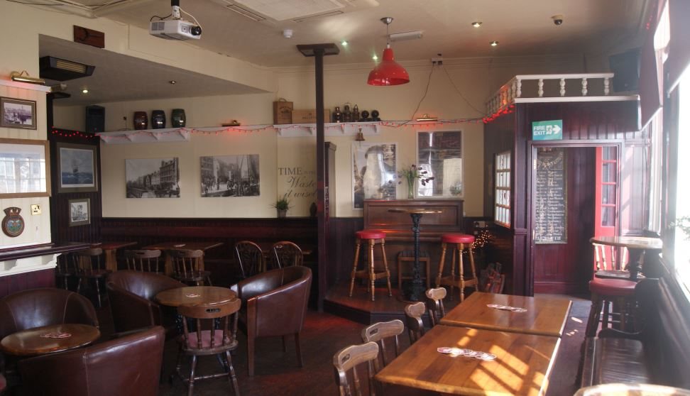 Interior of Admiral McBride showing wooden tables and chairs and walls covered with pictures.