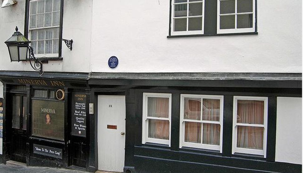 The black and white painted exterior of the Minerva Inn with large lantern hanging outside above the pavement.