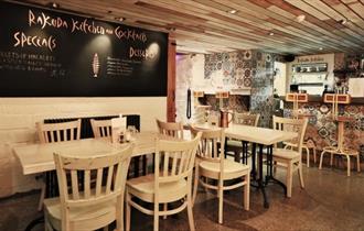 The inside of Bar Rakuda showing tables, chairs and a blackboard menu.