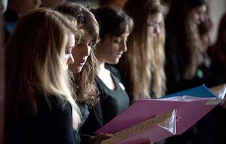 Choir members singing from sheet music