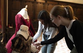 Visitors engaging with the Tudor costumes on display in the Great Hall at Buckland Abbey