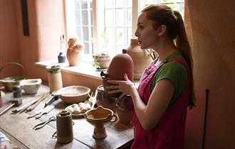 A volunteer explaining an artefact in Buckland Abbey's historic kitchen