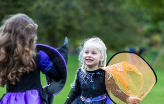 Two girls dressed in witches costumes playing