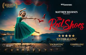 Women on pointe in blue dress and red ballet shoes in hand.