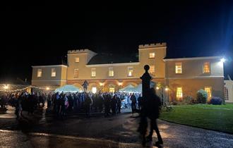 Crowd gathered in Pentillie's courtyard which is lit up ready for Christmas carols.