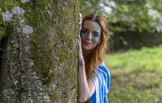 A water sprite looking out from behind a tree