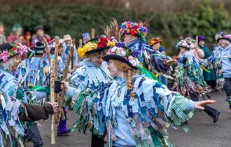 Members of the Dartmoor Border Morris dancing together in their ribbon-covered outfits